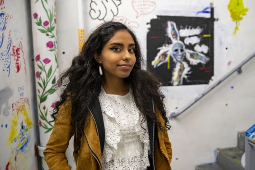 Rishika stands in the art-covered stairwell of the List Building